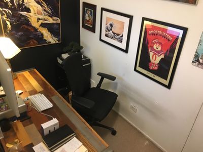 An office chair up against the wall with many photos on the wall