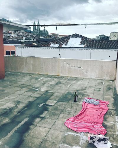 View of a sunbathing towel, laptop and bottle of wine on a rooftop. The background is Quito, Ecuador's capitol building and ominous cloudy sky.